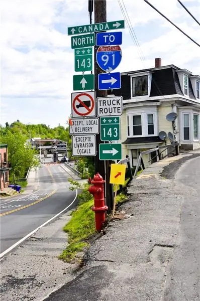Дорожные знаки в Дерби Лайн, Вермонт. В конце дороги видно здание канадской таможни