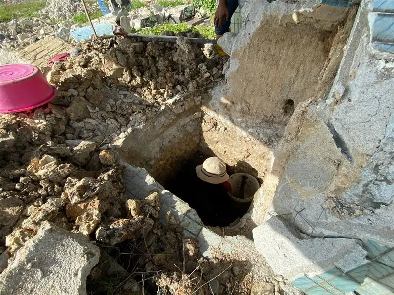 Рабочий спускается в полузатопленную могилу