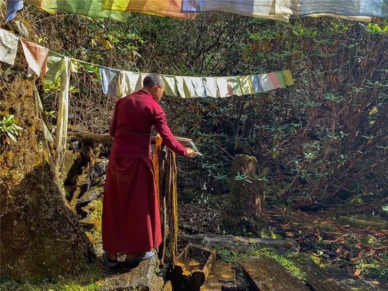 Монах набирает святую воду из источника в монастыре