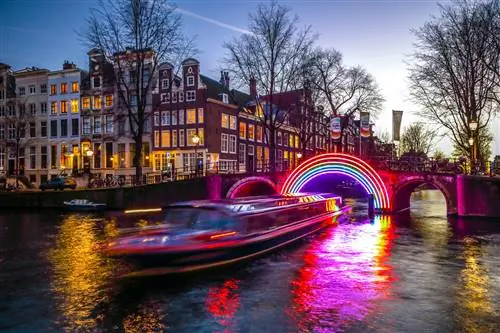 Лодка, проплывающая сквозь праздничные световые инсталляции на амстердамском канале ночью