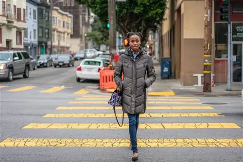 Молодая чернокожая женщина переходит улицу в районе Мишн в Сан-Франциско.