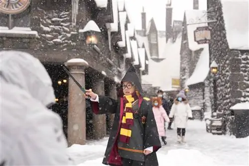 Ребенок, одетый как Гарри Поттер, держит палочку в снегу в Universal Studios, Пекин, Китай.