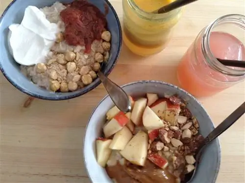 Две миски с овсянкой, каждая из которых покрыта разными начинками, включая фундук, йогурт и нарезанное яблоко.