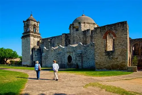Два человека идут по территории исторического здания Миссии.