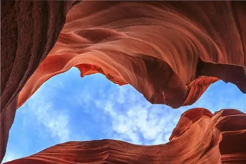 Яркие красные скалы несутся и кружатся над головой под ярко-голубым небом.