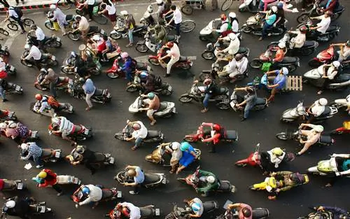 Вид сверху на очень оживленную дорогу в час пик в Хошимине. Дорога заполнена людьми на скутерах, у большинства из них не менее двух человек на каждом велосипеде.