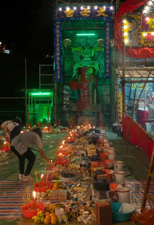 Женщина зажигает ароматическую палочку на улице в Гонконге, чтобы отогнать злых духов во время Фестиваля голодных духов.