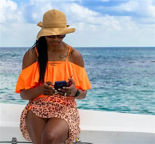 Женщина смотрит в свой телефон во время путешествия к Барьерному рифу в Белизе.