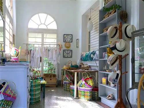 Совершенно белый интерьер бутика Alma наполнен одеждой, висящей у окна, вешалкой для шляп с панамами, столом, заставленным сумками и шляпами; выбор магазинов в Гаване изобилует