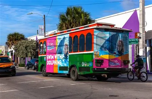 Вид сзади на красочный троллейбус, проходящий через Художественный район Винвуд, Майами, Флорида, США.