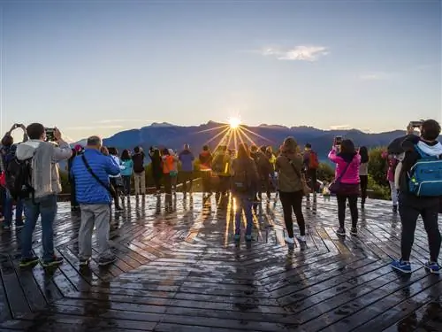 Группа туристов направляет камеры на восход солнца над горными вершинами.
