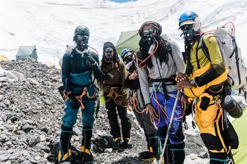 Члены команды Full Circle Everest стоят вместе на скалистой земле во время восхождения на вершину