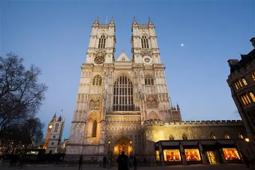 Огромный готический фасад здания собора с двумя большими башнями, взметнувшимися вверх в сумерках.