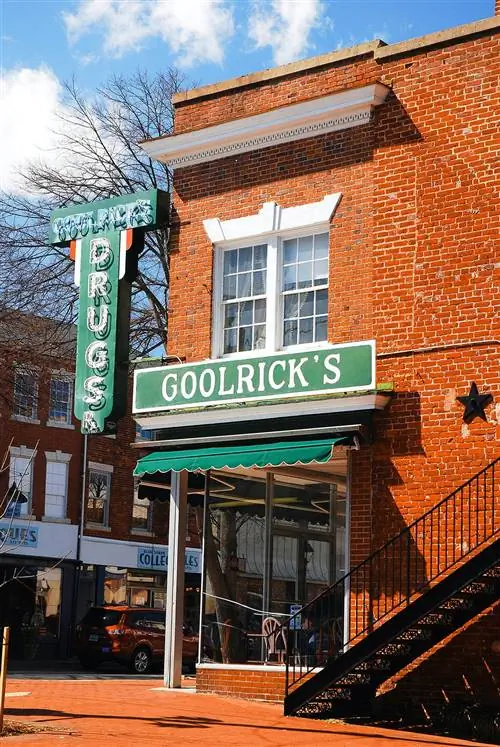 фасад из красного кирпича и зеленая неоновая вывеска с надписью «Аптека Гулрика»