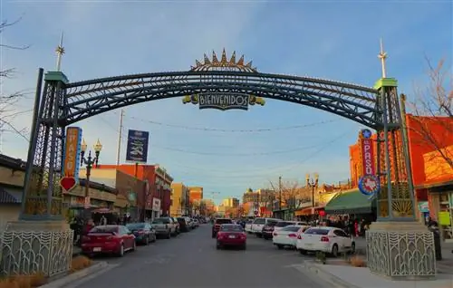 На городской улице с магазинами по обеим сторонам доминирует красочная арка на переднем плане, приветствующая посетителей Эль-Пасо, штат Техас.