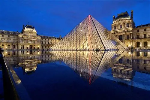 Пирамида Гранд подсвечивается ночью перед главными зданиями Лувра.