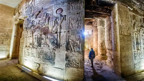 Подробные рельефные иероглифы на стене храма, когда мимо проходит человек