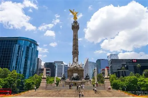 обелиск, увенчанный золотым ангелом, стоит в окружении высотных зданий