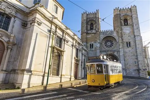 Типичный желтый трамвай перед Sé de Lisboa в Лиссабоне, Португалия