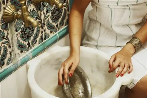 Женщина держит таз для умывания в хаммаме