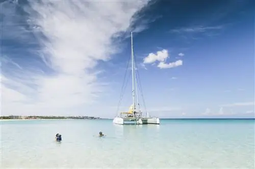 Голубая морская вода и белый парусник на заднем плане, вид из голубых вод Карибского моря