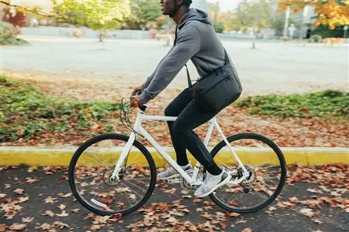 Взрослый темнокожий мужчина наслаждается велосипедной прогулкой в солнечный осенний день на тихоокеанском северо-западе. Осенние листья светятся в лучах солнца. Снято в Сиэтле, штат Вашингтон, США.