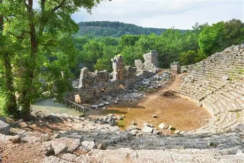 Полуразрушенный амфитеатр напротив осыпающейся каменной стены.
