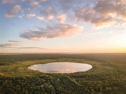 Солнце садится над идеально круглой лагуной, окруженной джунглями.