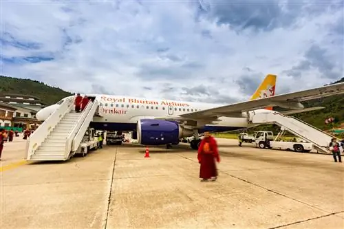 На этом дневном снимке показаны пассажиры, прибывающие в международный аэропорт Паро в Бутане рейсом Royal Bhutan Airlines (Drukair). Самолет представляет собой Airbus A319 с регистрационным номером A5-JSW. Ко всем людям на фотографии применено размытие.