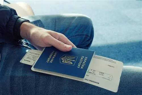 Молодые люди в джинсах держат в руках заграничный паспорт Украины с прикрепленным к нему авиабилетом.