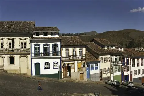 Женщина проходит мимо красочной колониальной архитектуры в Ору-Прету, Бразилия.