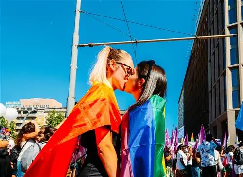 Женщины целуются на гей-параде в Милане с радужными флагами на плечах