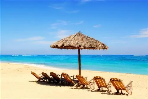 Зонтик и деревянные стулья на тропическом карибском пляже в Магуана-Бич, Куба