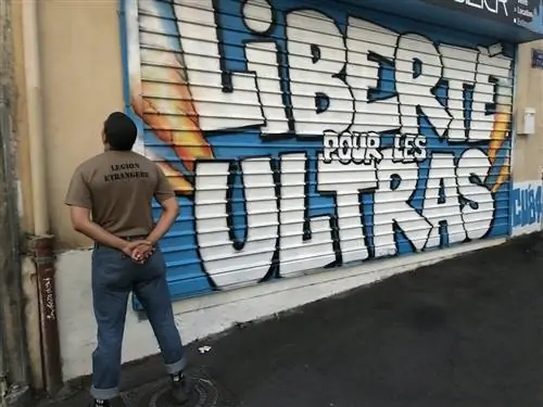 Мужчина стоит спиной и смотрит на граффити с надписью Liberté pour les Ultras