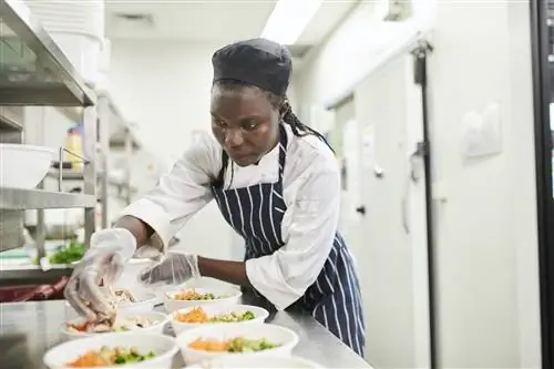 Женщина африканского происхождения готовит еду на кухне ресторана, Мельбурн, Виктория, Австралия.