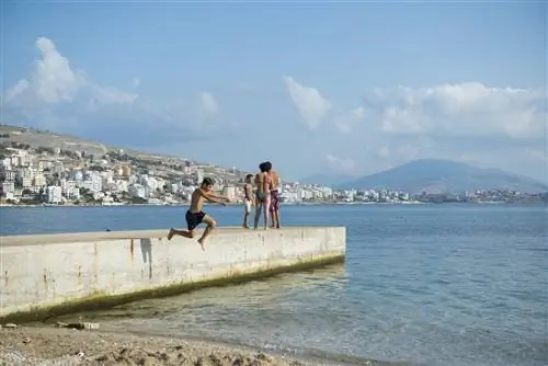 Мальчик прыгает с пирса в Средиземное море в Саранде (Саранда), Албания.