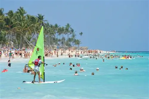 Турист учится виндсерфингу на оживленном пляже Пунта-Кана