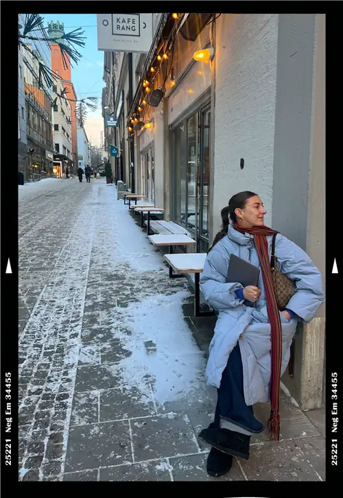 Автор в пальто и с ноутбуком в руке стоит зимой на улице Стокгольма.