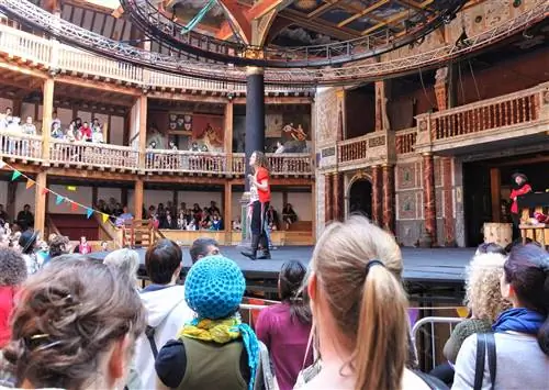 Зрители наблюдают за исполнителем на сцене Shakespeare's Globe в Лондоне.