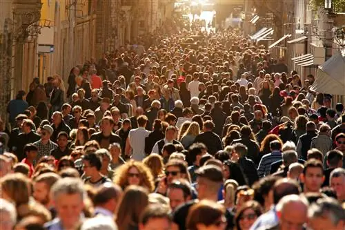 Большая группа людей толпится на центральных улицах Рима в солнечный день.