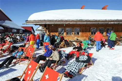 Лыжники отдыхают на шезлонгах в снегу в ресторане на горе Титлис