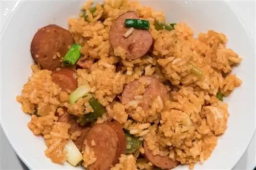 Каджунская колбаса и рис, украшенные зеленым луком (он же джамбалайя), подаются в простой белой миске.