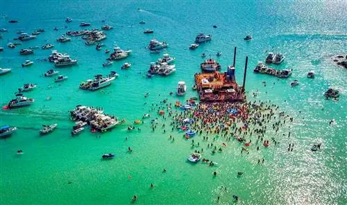 Аэрофотосъемка лодок и людей в воде вокруг большого деревянного плота