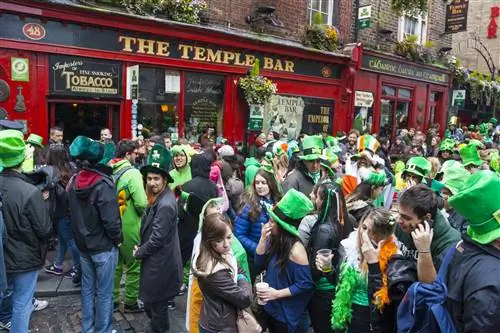 Толпы собираются у паба Temple Bar, одетые в огромные зеленые шляпы, чтобы отпраздновать День Святого Патрика.