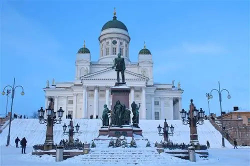 Снежный, сумеречный снимок Туомиокиркко, Хельсинки, со статуей царя Александра на среднем плане.
