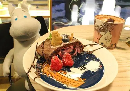 Торт на посуде с муми-троллями в кафе Mumin Kaffe в Хельсинки, а на столе - мягкая игрушка с муми-троллями.