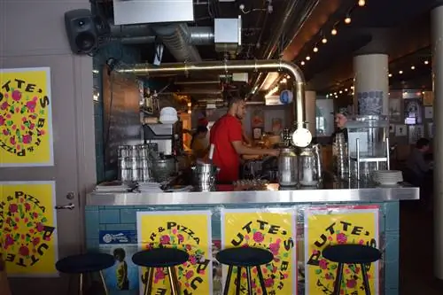 Сотрудник, работающий за стойкой из нержавеющей стали в Putte's Pizza.