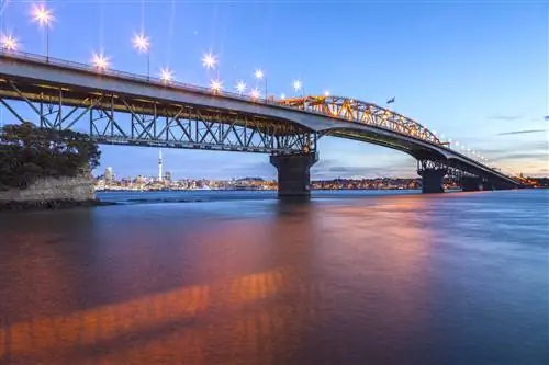 Мост через гавань Окленда в сумерках от мыса Норткот с розовым светом, отражающимся в воде