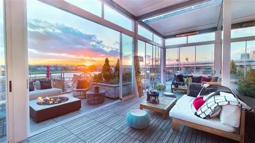 Огромные раздвижные стеклянные двери убираются в сумерках, открывая внутреннее и внешнее пространство, с элегантной современной мебелью и местом для костра в баре на крыше Terazza.