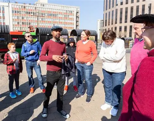 Чернокожий гид из Южной Африки стоит в центре города с группой посетителей во время одной из пешеходных экскурсий JoburgPlaces по Йоханнесбургу.